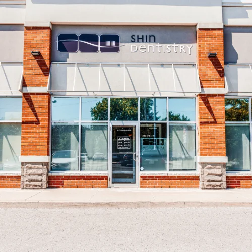 exterior storefront view of shin dentistry building with brick pillars and large glass windows