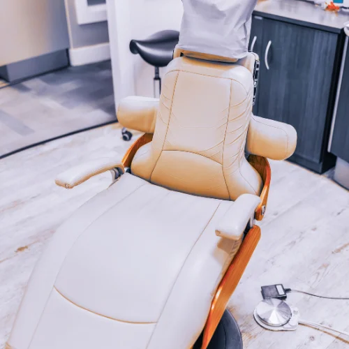 front view of beige cushioned dental patient chair with wooden side paneling
