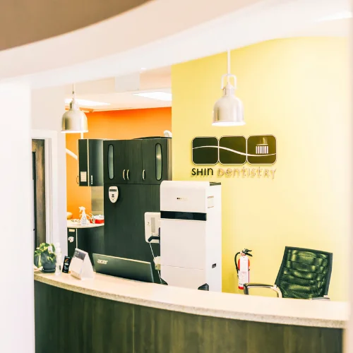 reception desk area at shin dentistry with yellow feature wall and black office chair