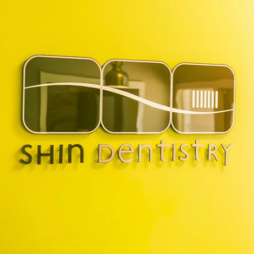 shin dentistry logo display mounted on vibrant yellow interior wall